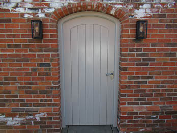 Painted arched door inset into a garden wall, handmade in Shropshire